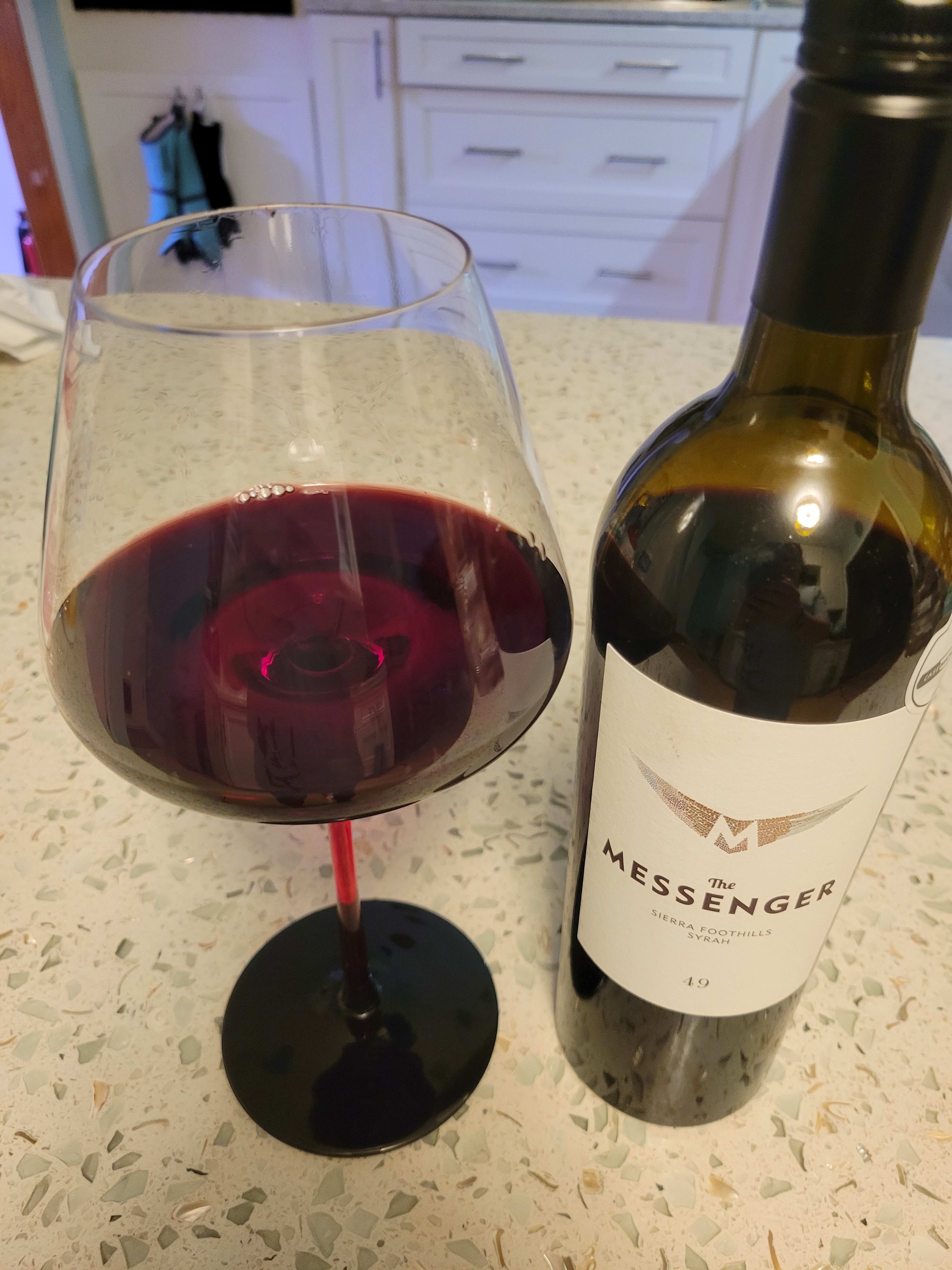 The Messenger bottle and a glass with red wine in it.