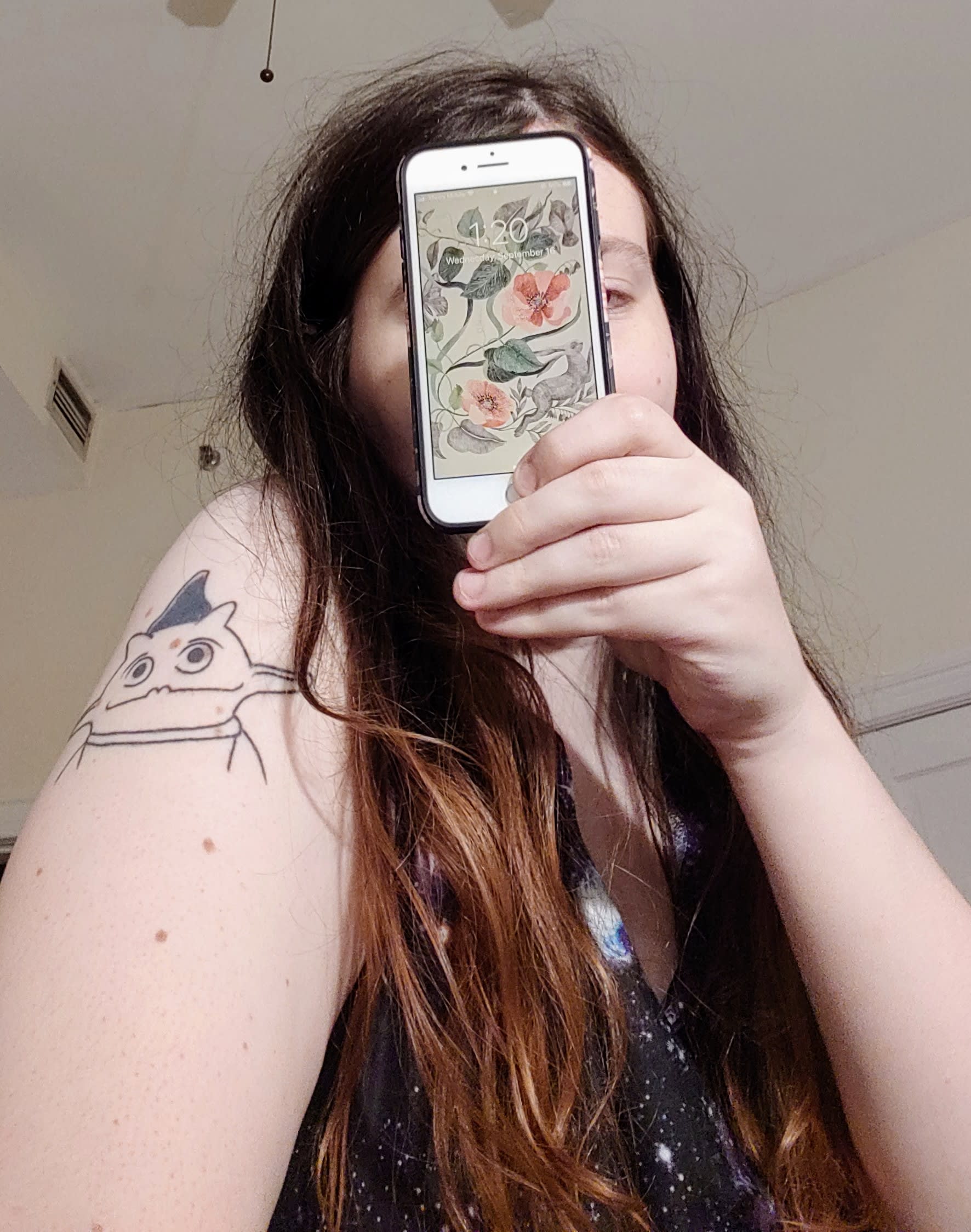 photo of woman with Irk tattoo holding phone with date on it over face