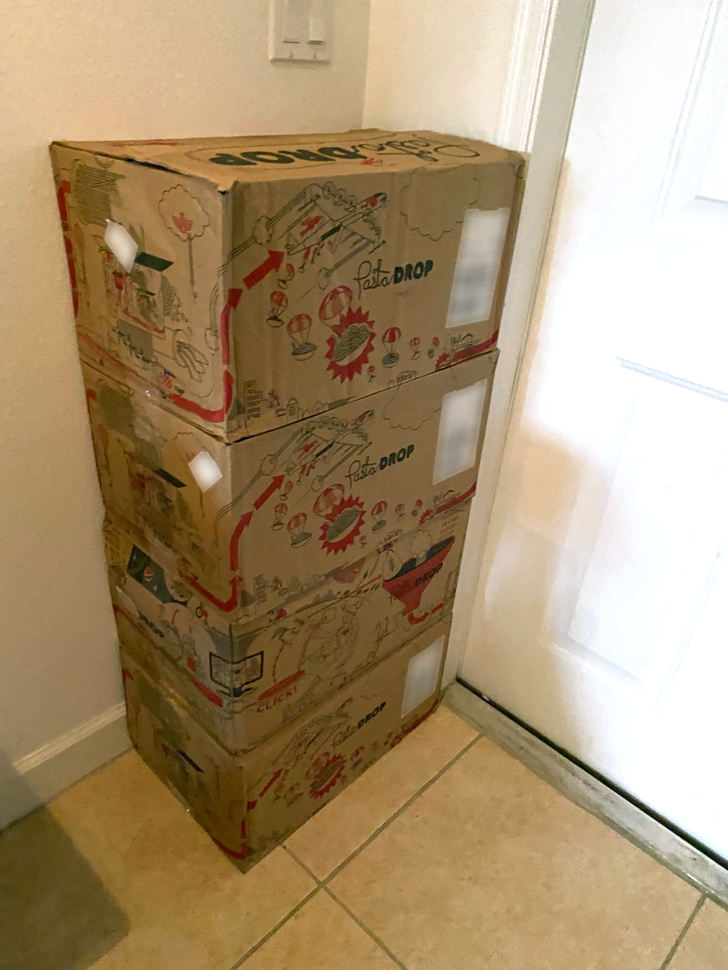 A stack of four Pasta-Drop boxes stacked in the corner of a vestibule