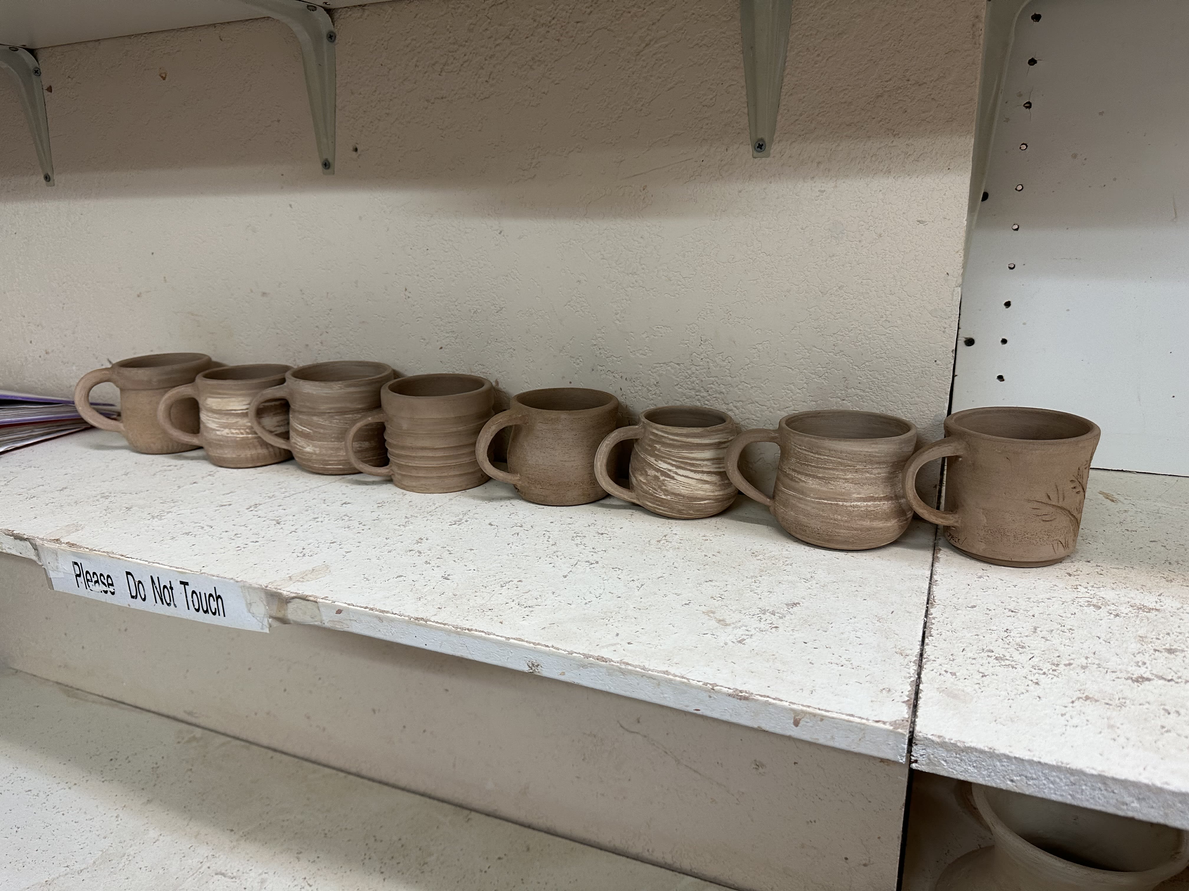 Line up of eight unfired clay mugs