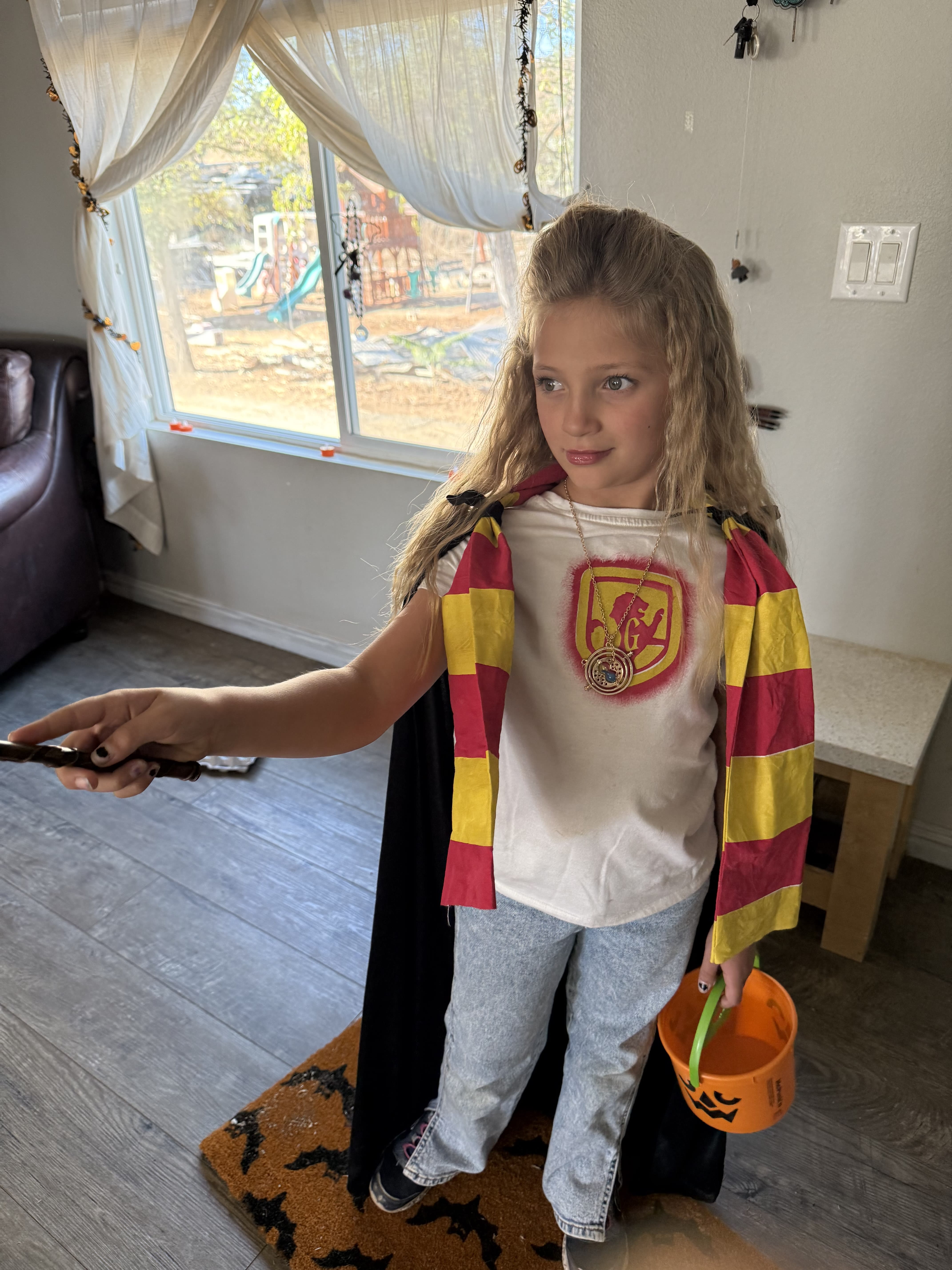 Wands at the ready: Posing for a Halloween pic in "Gryffindor" regalia, a young girl wields a plastic wand and an empty trick-or-treat bucket