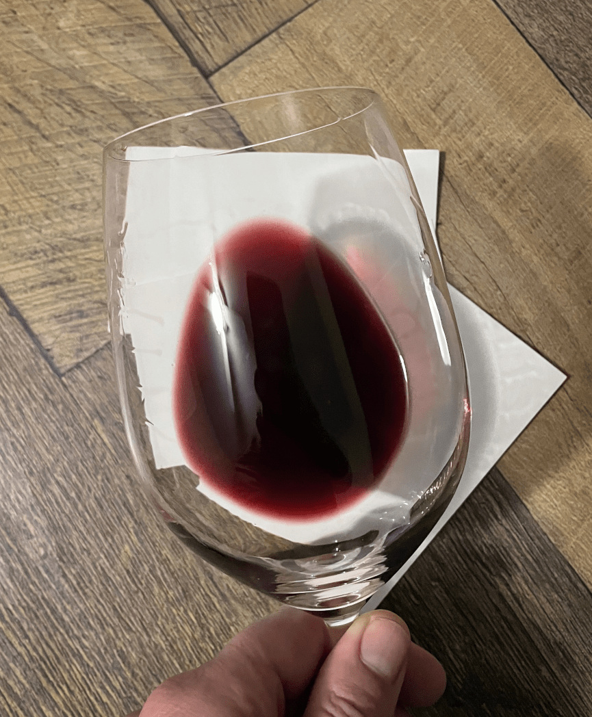 Photo of the Bonarda in a glass, held over a white background to clearly show color and opacity